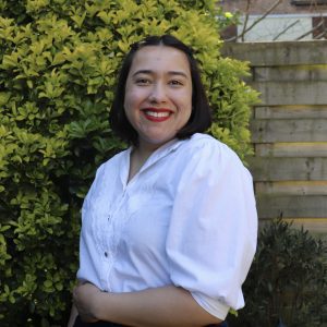A young woman with a white shirt, smiling, with black short hair.